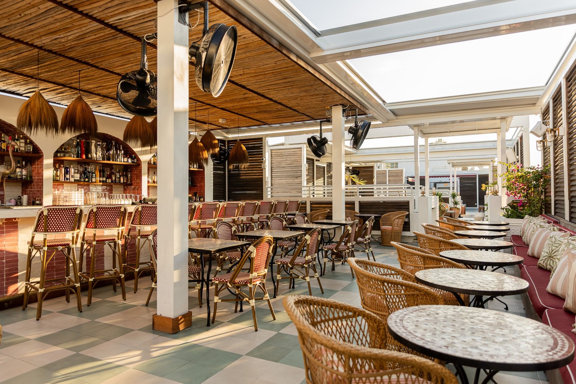 a bar with a tiled floor, barstools, tables and chairs, and a sofa