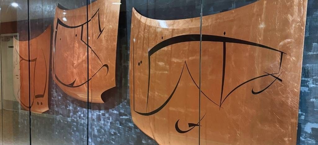 Large wall installation featuring stylized Indigenous copper-toned artwork.