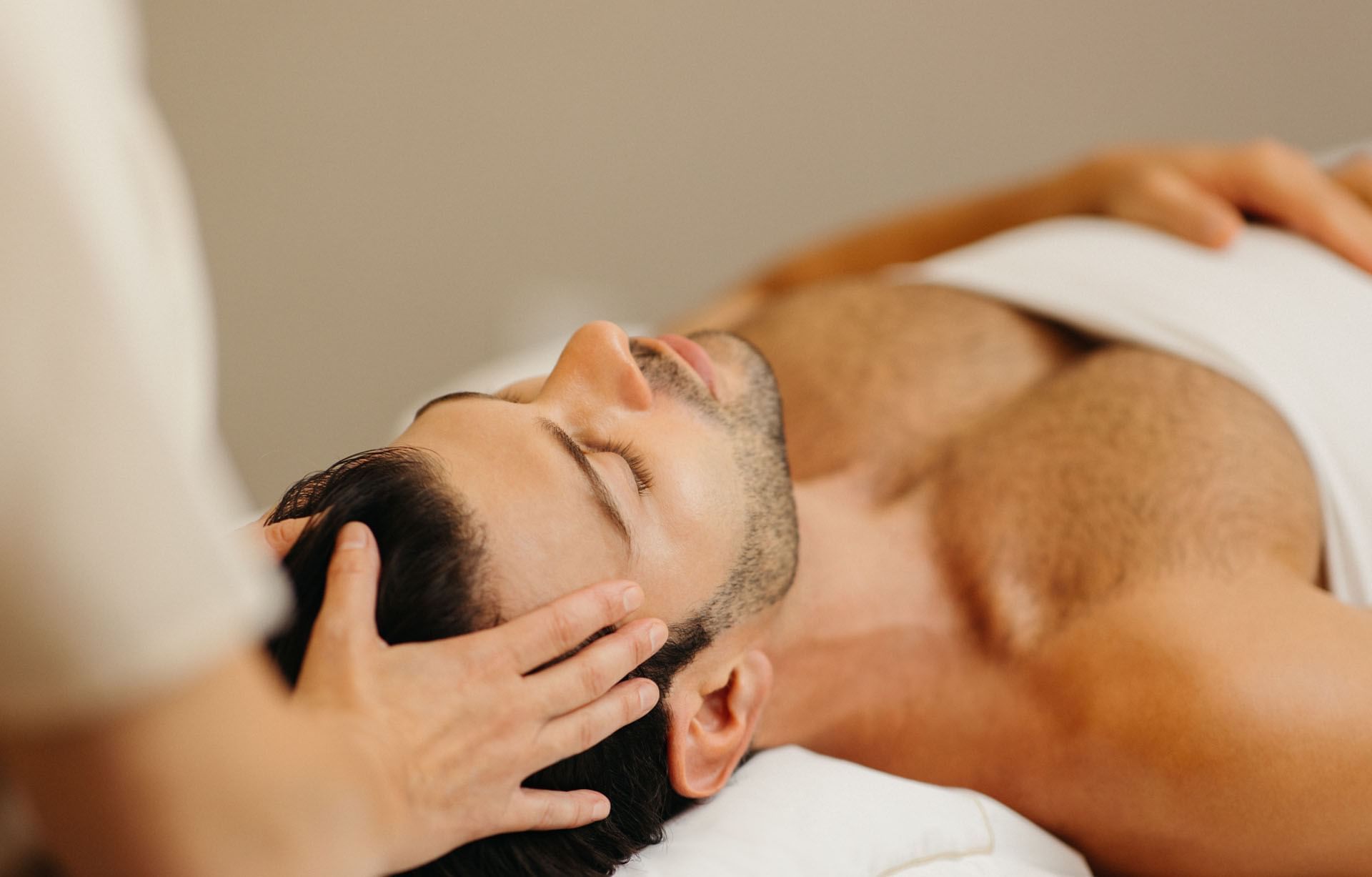 Man relaxing on massage table with therapist performing head massage treatment at Guerlain Spa at Hotel X Toronto