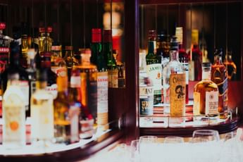 Bar cabinet display featuring rows of assorted liquor bottles, including whiskey, tequila, and vodka, at The Library Bar