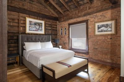 King bed with comfy pillows, brick wall & window in a residence at Retro Suite Hotel