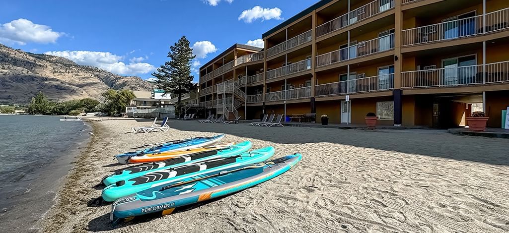Paddleboards lined up along the shoreline on the hotels private beach with the hotel building in the background