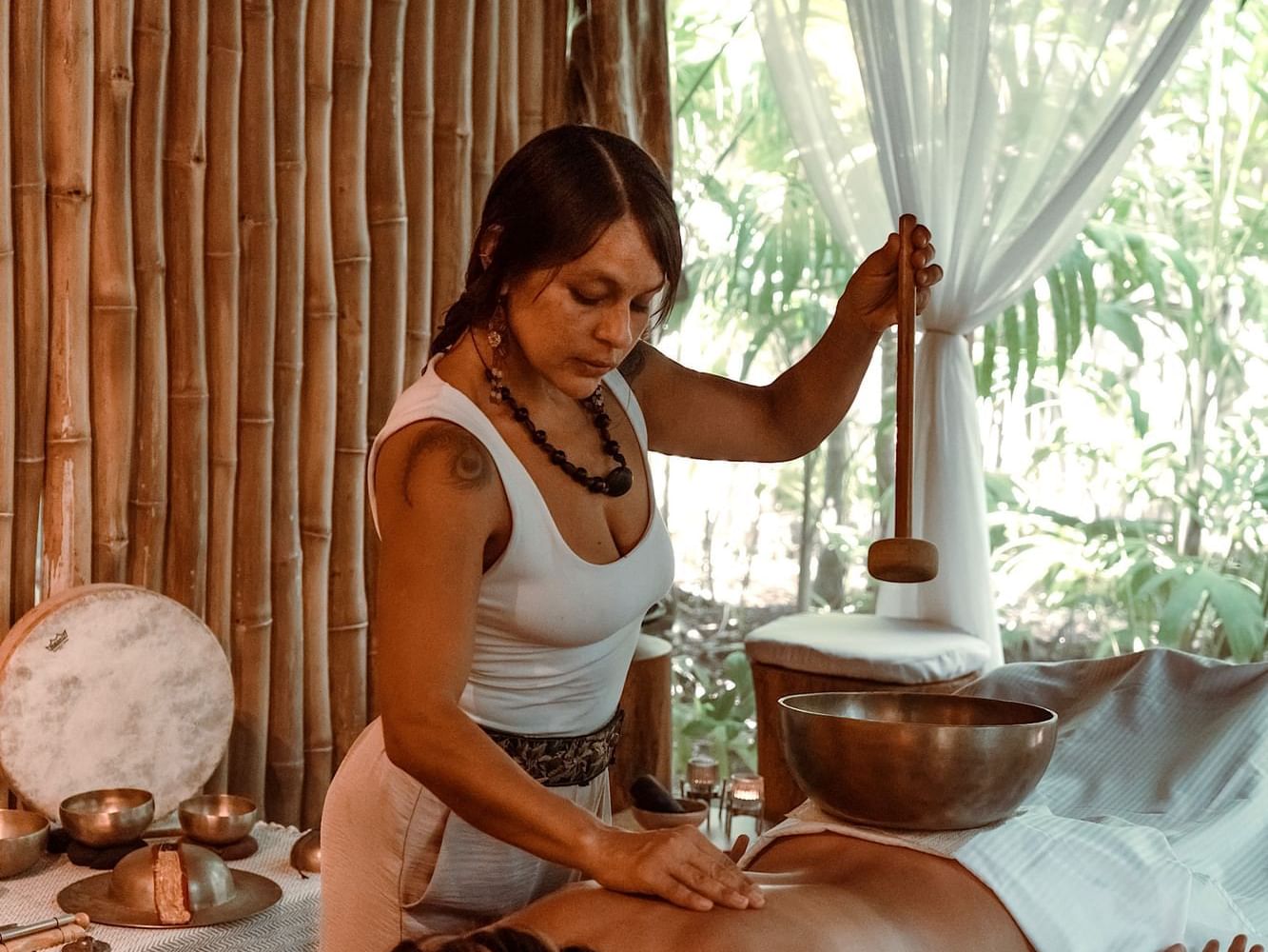 Woman receiving a massage in a bamboo-walled room at Cala Luna's Vitality Retreat.