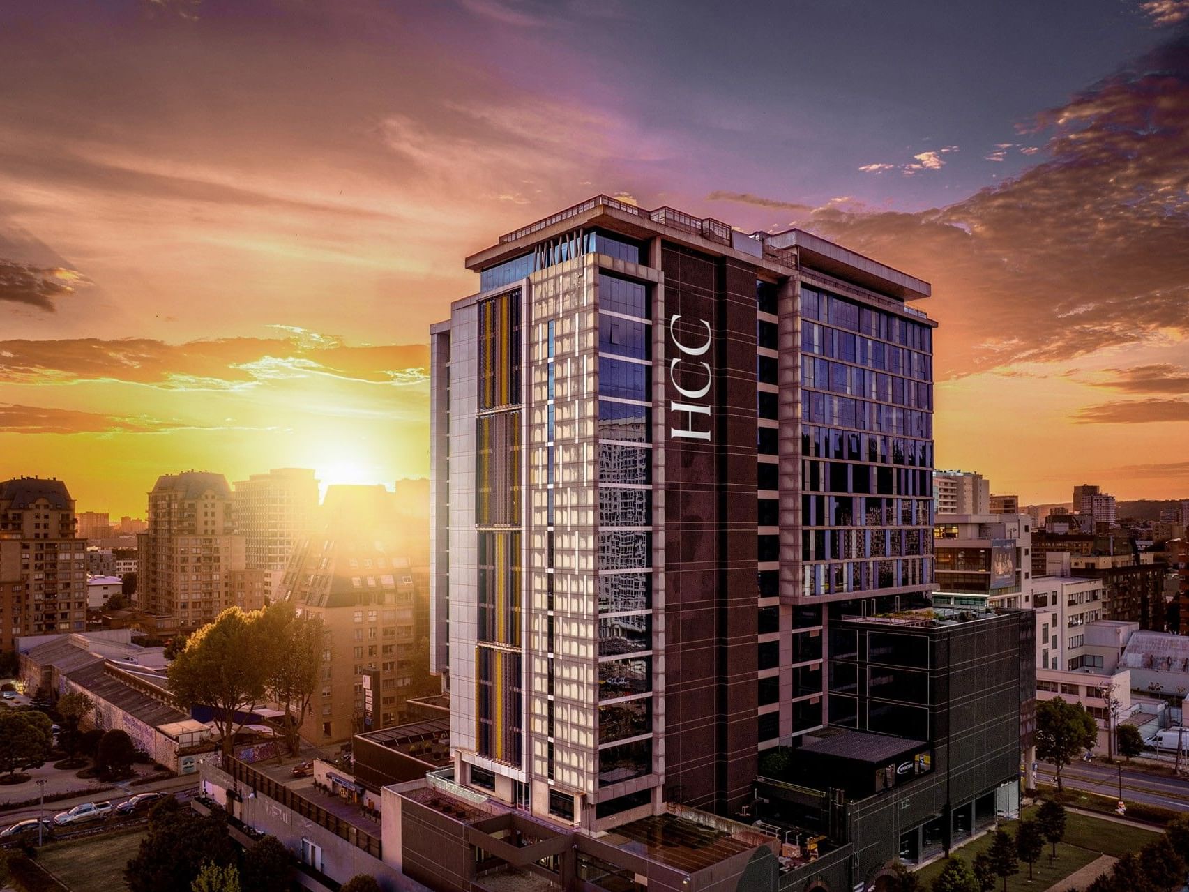 Hotel HCC Costanera Concepción, con vistas panorámicas de la ciudad y el cielo al atardecer como telón de fondo.