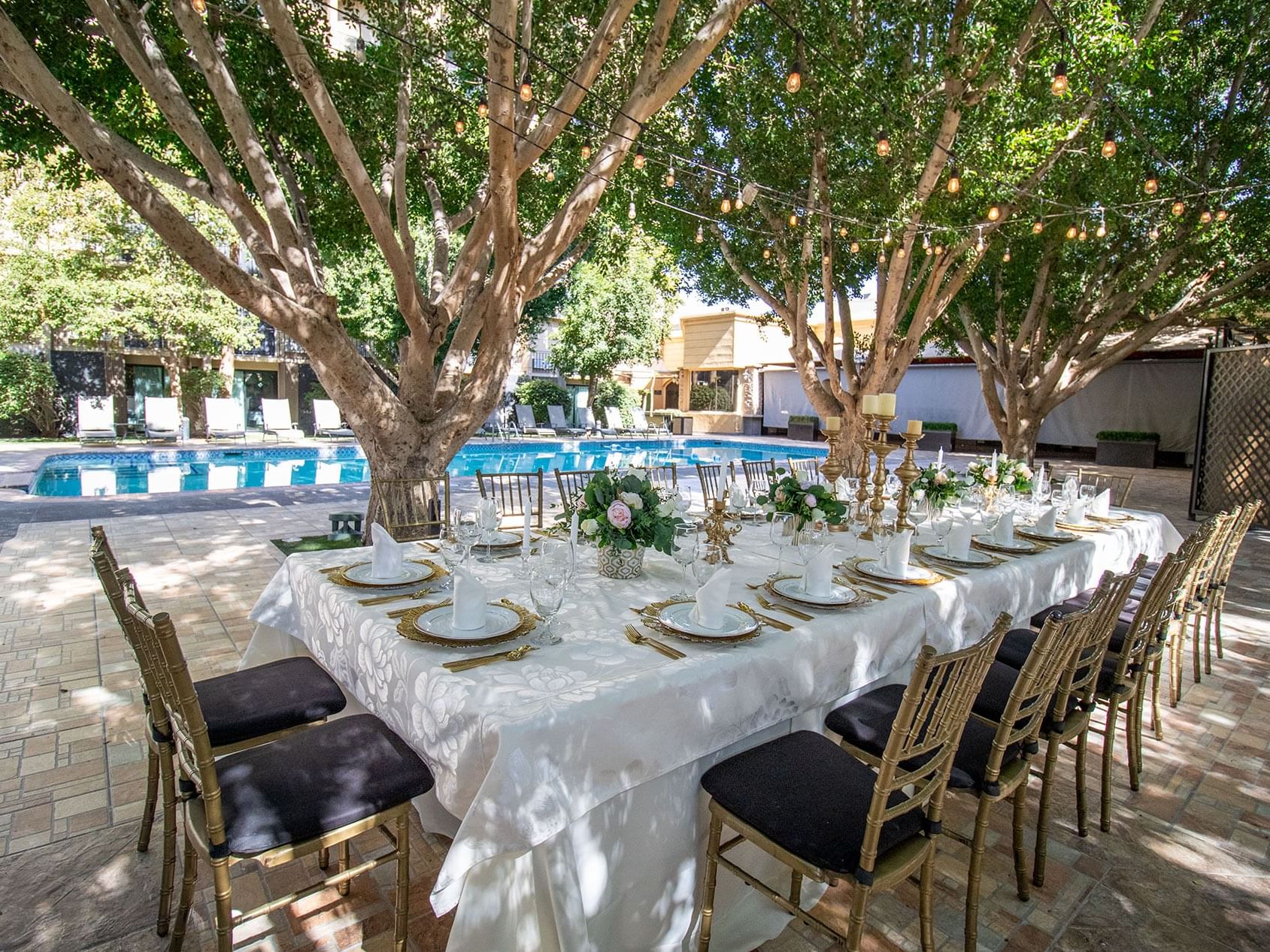 Elegante mesa a la sombra de los árboles junto a la alberca