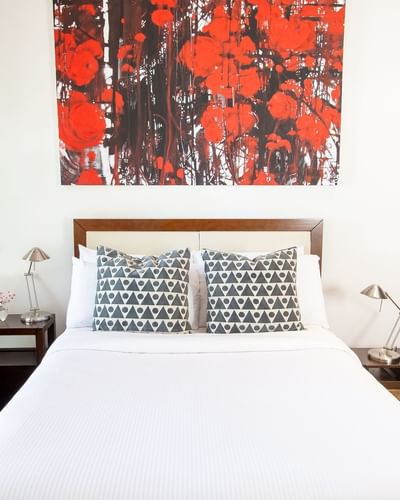 a queen bed with two decorative pillows and a bright red, black