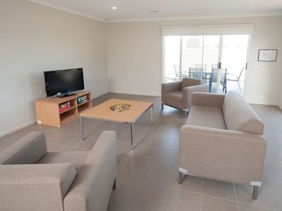 Living room with couch, TV, and table at La Trobe University Regional Housing – Shepparton.