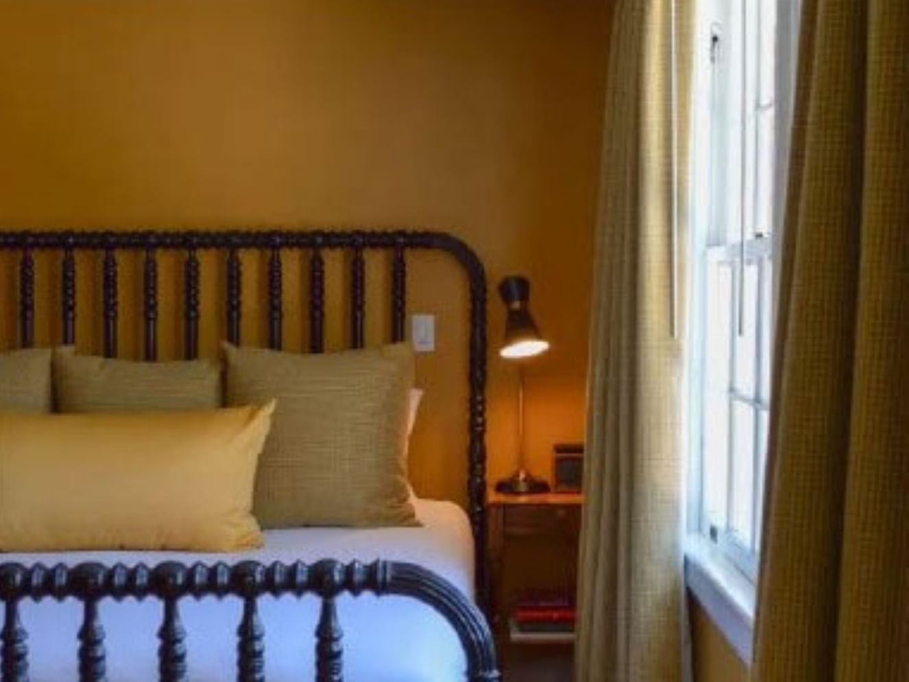 Cozy bed & nightstand by window in James Monroe at The Clifton
