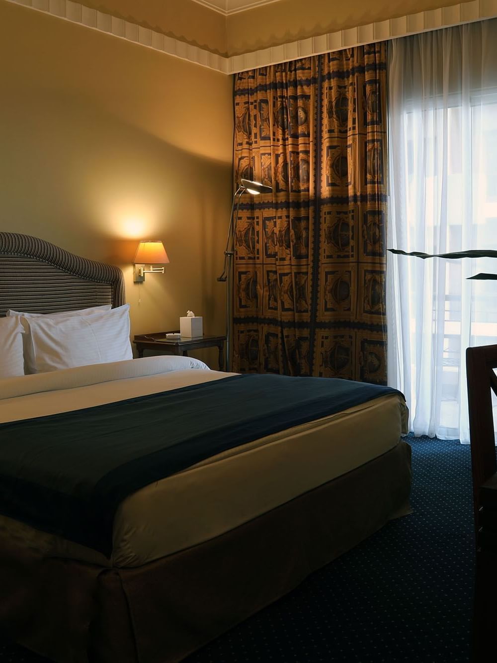 King bed with a side table by a window in Junior Suite at Warwick Palm Beach Hotel