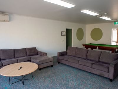 Two gray couches, table, and pool table in lounge area at La Trobe University - Orde House.