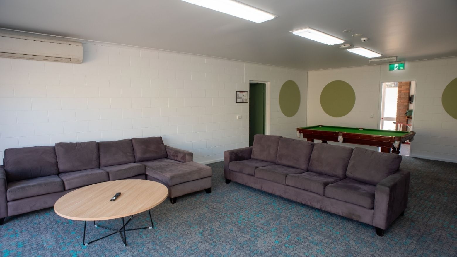 Two gray couches, table, and pool table in lounge area at La Trobe University - Orde House.