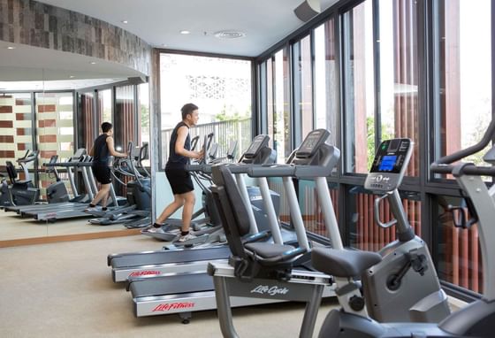 Man exercising on a treadmill in a fully equipped gym at Eastin Tan Hotel Chiang Mai