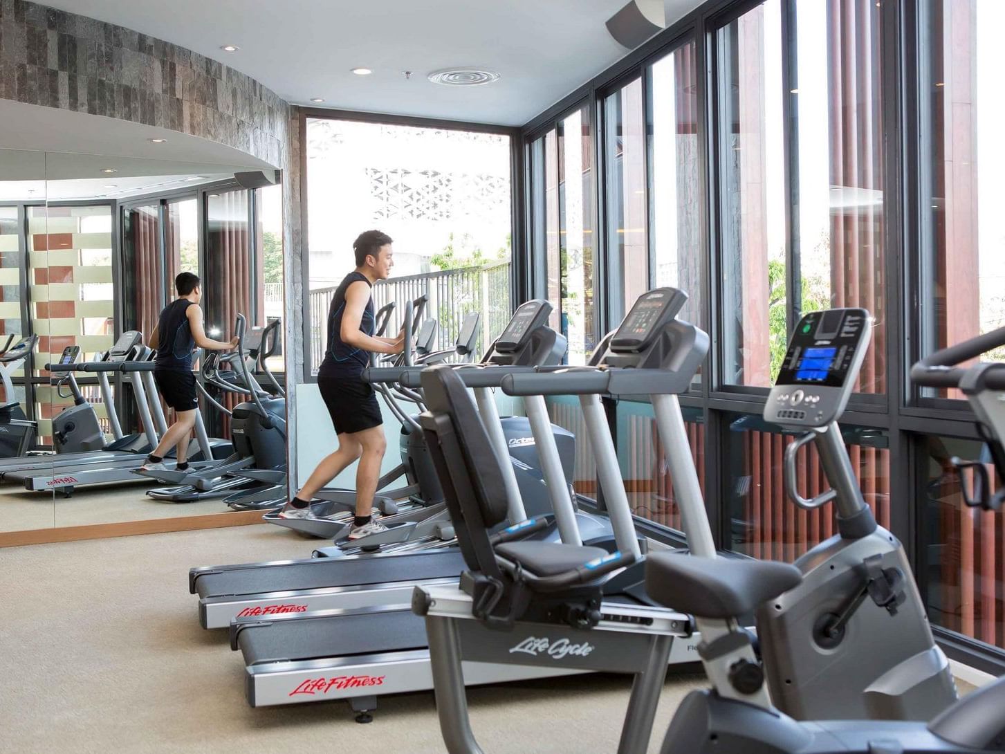 Man exercising on a treadmill in a fully equipped gym at Eastin Tan Hotel Chiang Mai