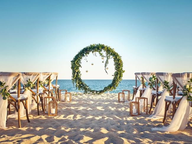 A breathtaking beach wedding setup at Hacienda del Mar Los Cabos with a circular floral arch at the altar