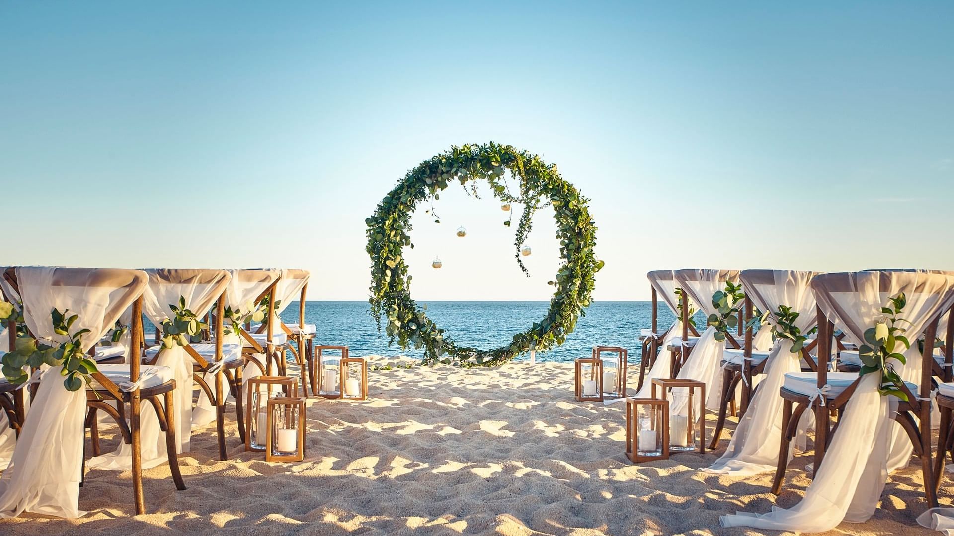 A breathtaking beach wedding setup at Hacienda del Mar Los Cabos with a circular floral arch at the altar