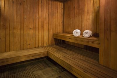 Interior of a sauna with two neatly rolled towels on a bench at Hotel Los Delfines & Casino