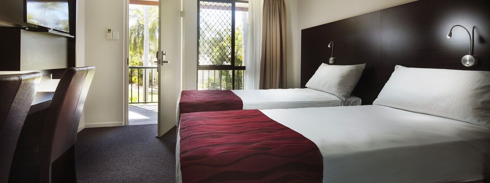 Superior Twin Room featuring two beds, a desk, a TV, and a balcony door leading to a view of Mercure Hotel Townsville