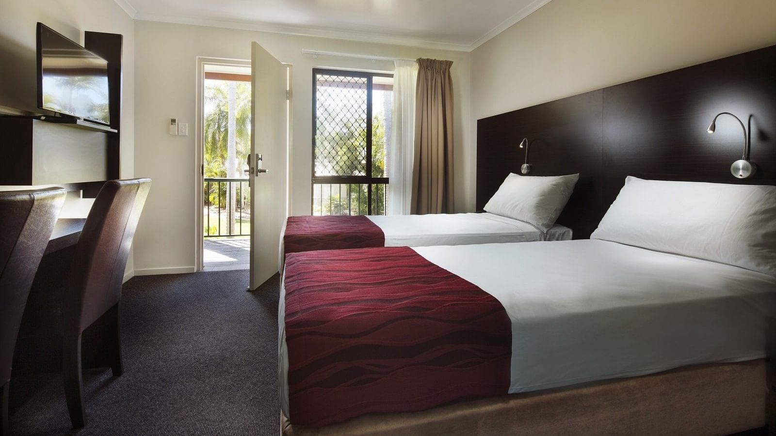 Superior Twin Room featuring two beds, a desk, a TV, and a balcony door leading to a view of Mercure Hotel Townsville