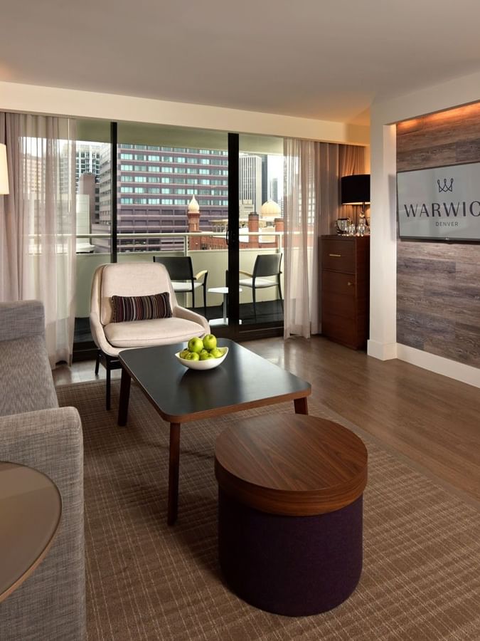 Modern living area with a sofa by a coffee table under a wall-mounted TV in Accessible Classic Rooms at Warwick Denver