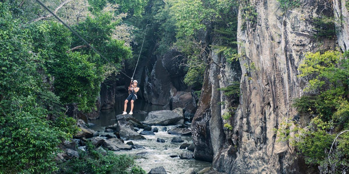 Lady zip lining over the river alongside the forest near Hotel Rio Perdido