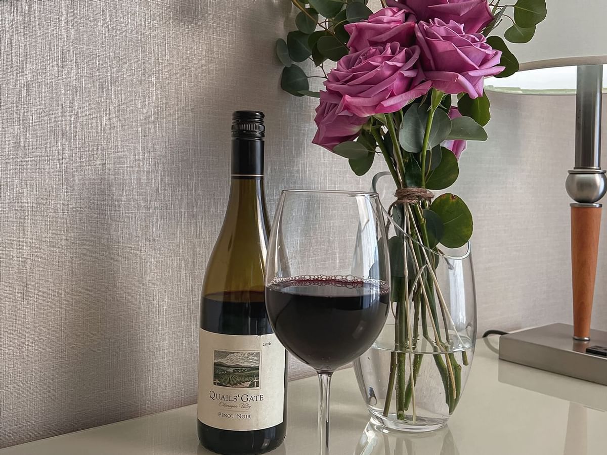 Wine bottle and wine glass with vase of roses on counter top