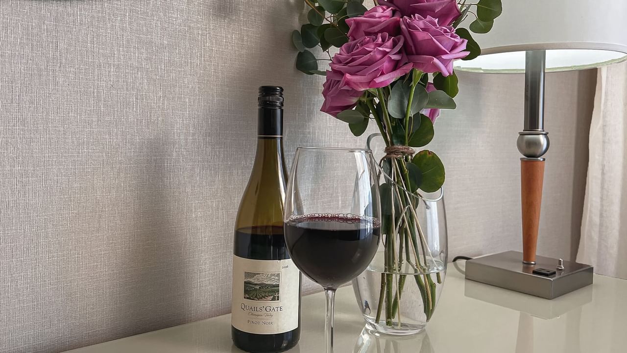 Wine bottle and wine glass with vase of roses on counter top