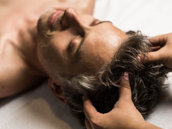 A man receiving a head massage at Warwick Le Crystal