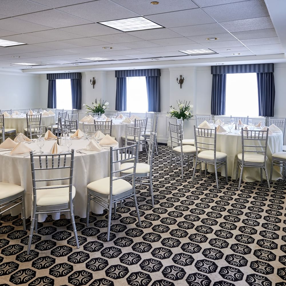 Elegantly set tables with white linens and silver chairs in the Frank Lloyd Wright Room at Warwick Allerton Chicago