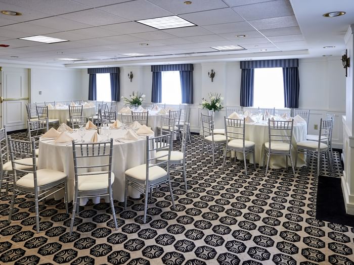 Elegantly set tables with white linens and silver chairs in the Frank Lloyd Wright Room at Warwick Allerton Chicago