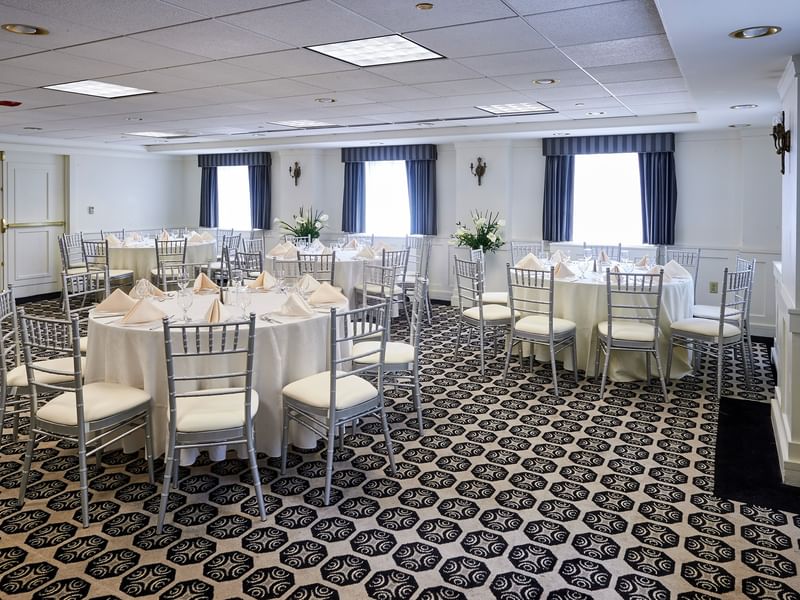 Elegantly set tables with white linens and silver chairs in the Frank Lloyd Wright Room at Warwick Allerton Chicago