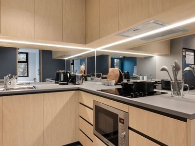Modern kitchen area with wooden cabinets and appliances at La Trobe University - North and South Apartments.