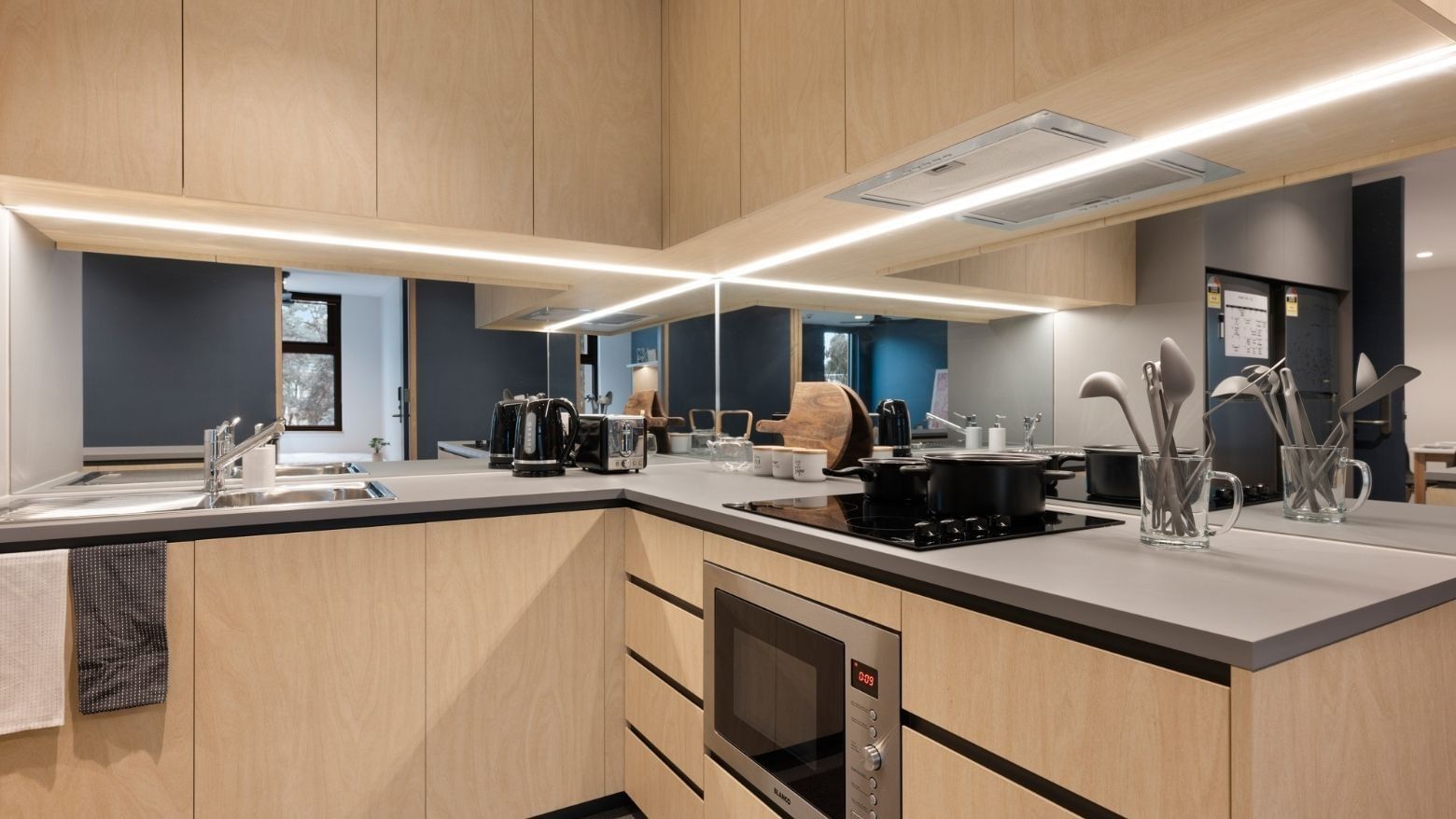 Modern kitchen area with wooden cabinets and appliances at La Trobe University - North and South Apartments.