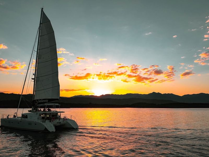Sailboat on waters in sunset with colorful sky and mountain silhouette near Pullman Port Douglas