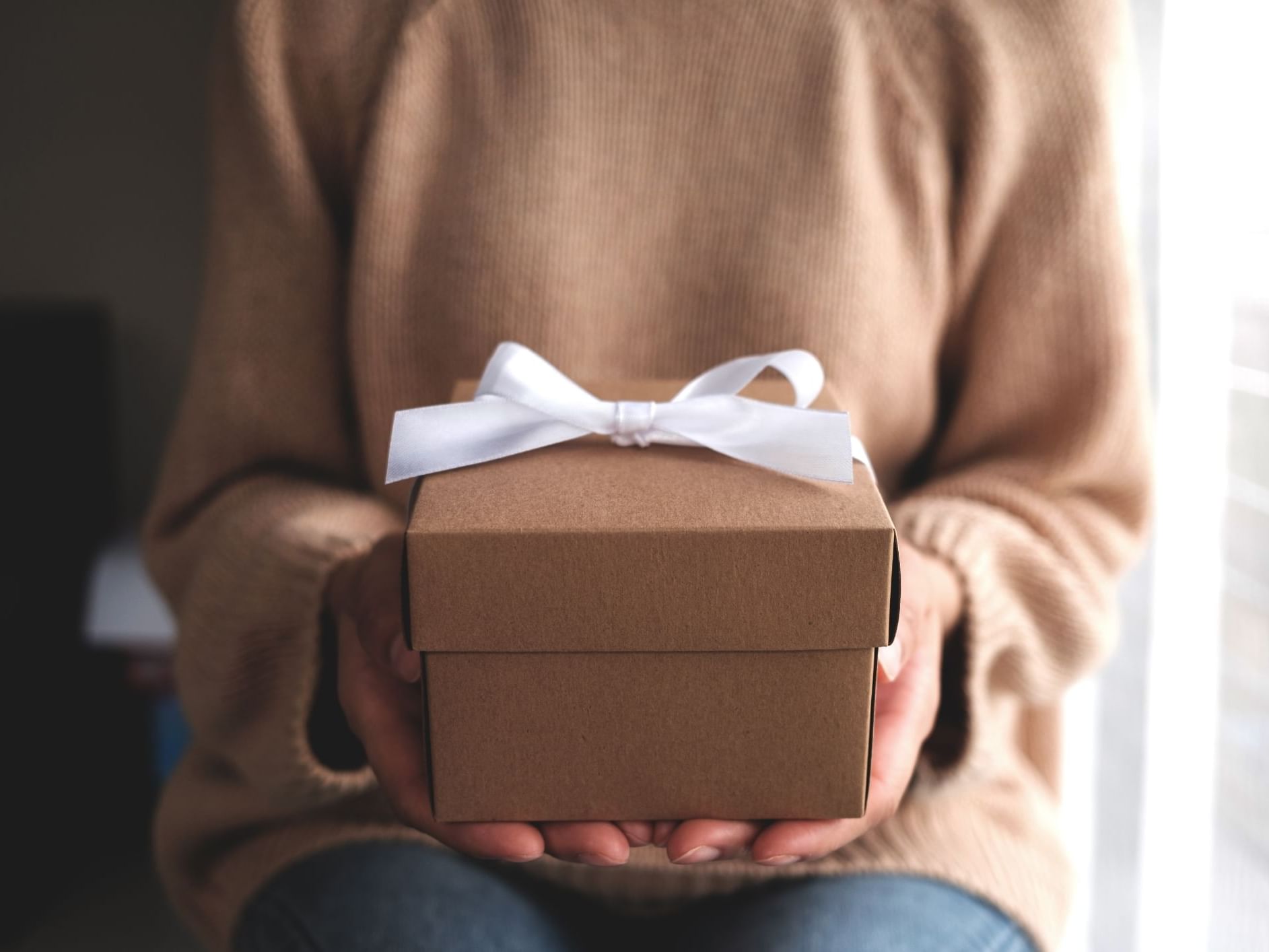 A woman holding a Gift box with a white ribbon in Hotel Grand Chancellor Townsville