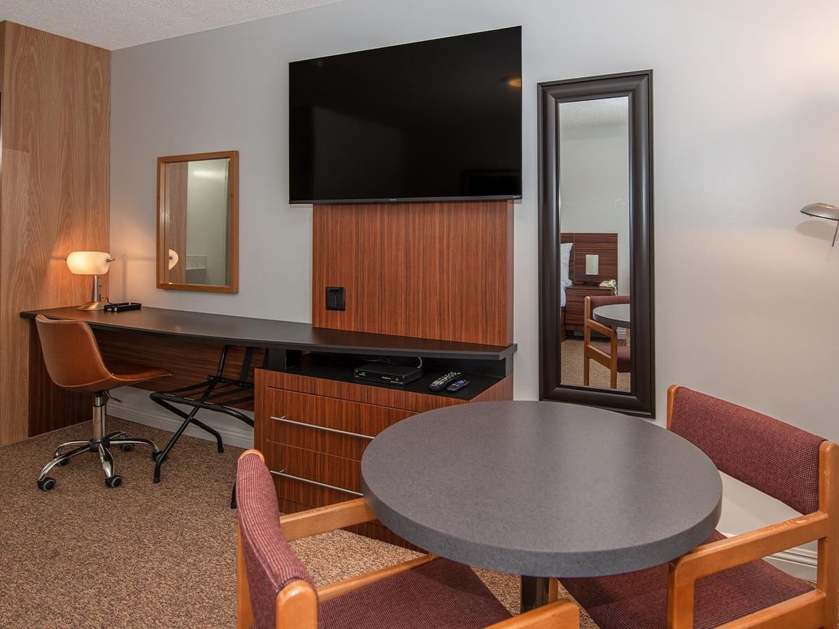 Guest room seating area with a wall-mounted TV, round table and chairs.