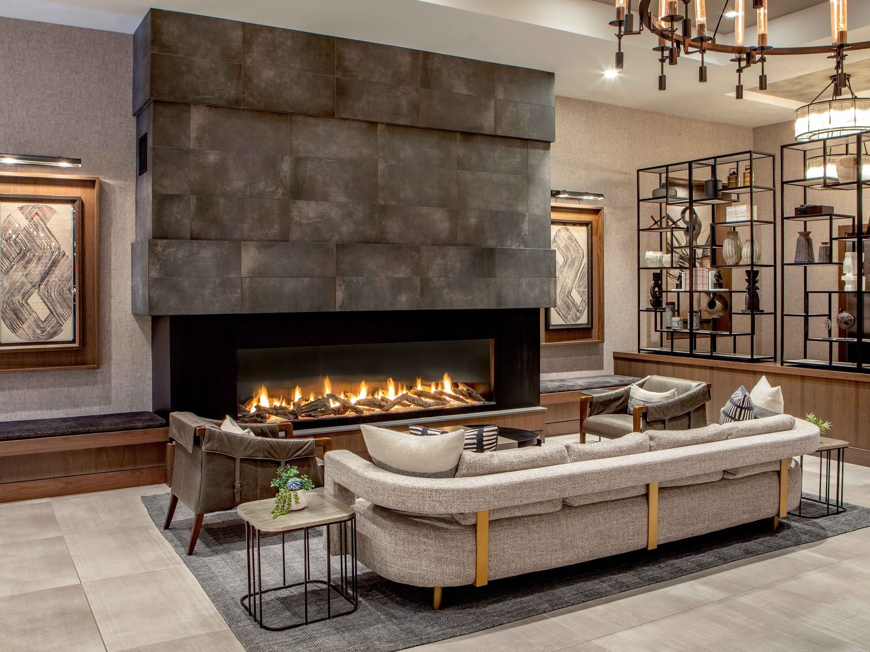Modern lounge area with fireplace, seating, and decorative shelving in a hotel lobby.