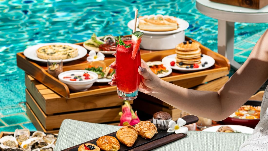 A person holding a drink with a backdrop variety of dishes at Sunway Resort