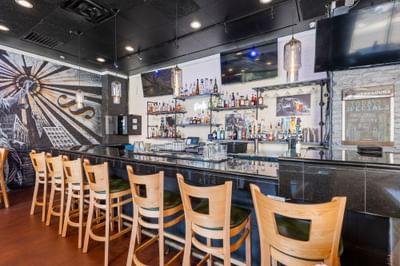 Interior of The Gavel at The Riverwalk Plaza Hotel featuring a bar with stools, a mural, and shelves with drinks