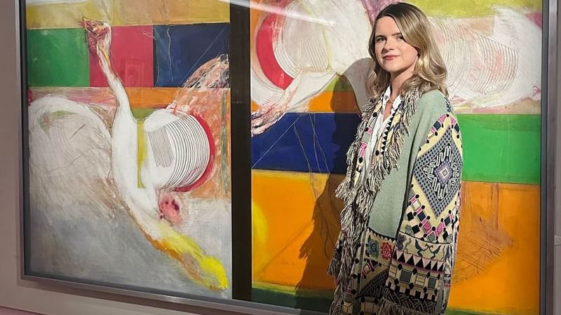Woman in a stylish patterned cardigan posing beside abstract art at The Londoner Hotel 