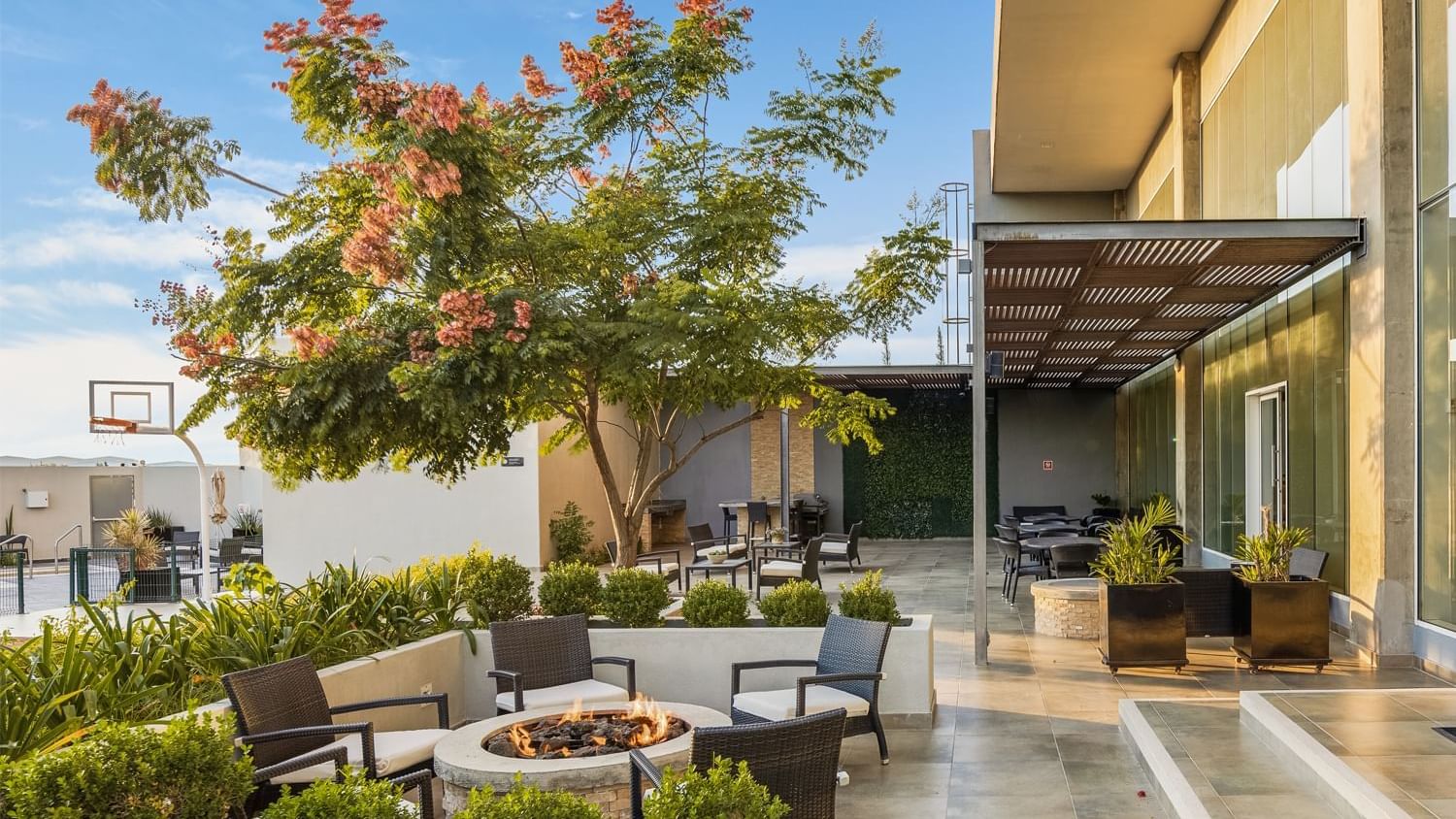 Outdoor space featuring a fire pit, seating, plants, and a basketball hoop at Fiesta Inn Suites Aeropuerto del Bajío