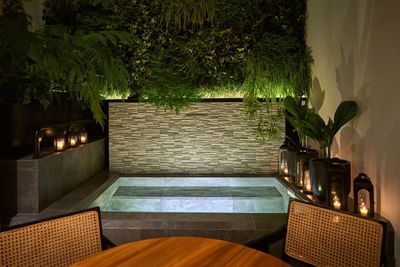 Luxurious outdoor jacuzzi, illuminated by candles and a green wall in Casa Cielo at Singular Signature Residences