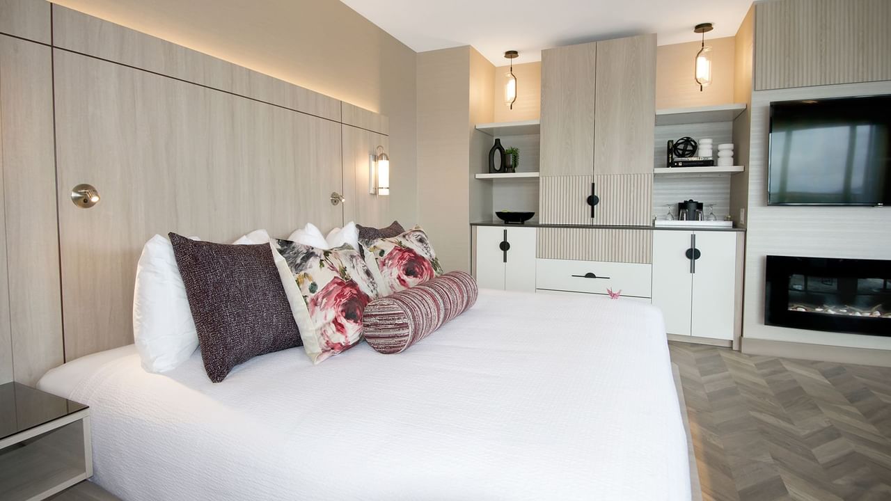 Hotel guestroom with king bed, TV, fireplace, and coffee maker