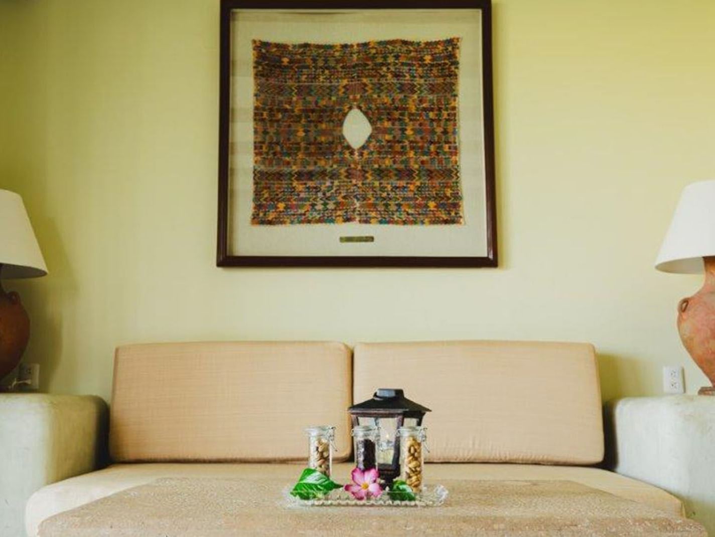 King Grand Class Suite living area, featuring a neutral sofa and framed textile art at Quinta Real Huatulco