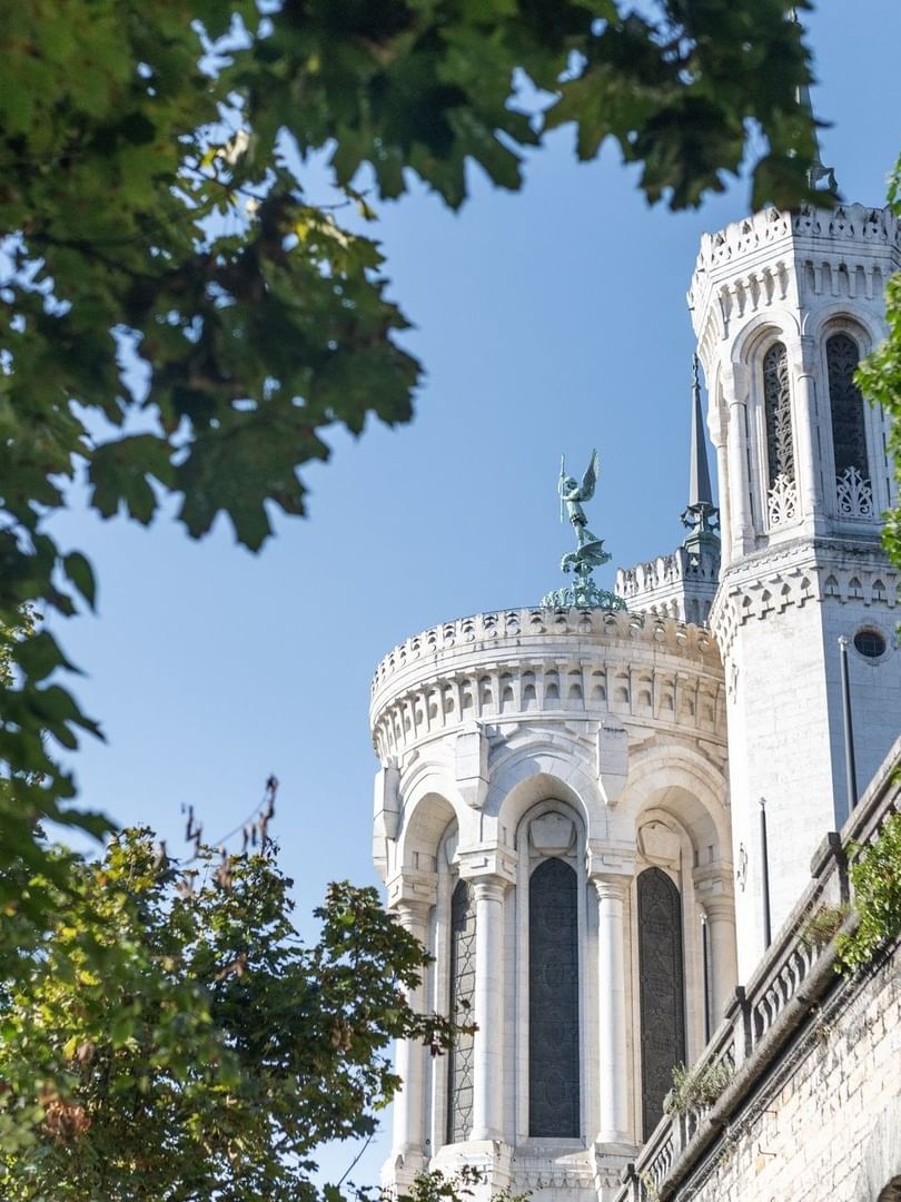 Exterior view of Basilica of Notre Dame of Fourvière, surrounded by lush greenery near Warwick Reine Astrid - Lyon