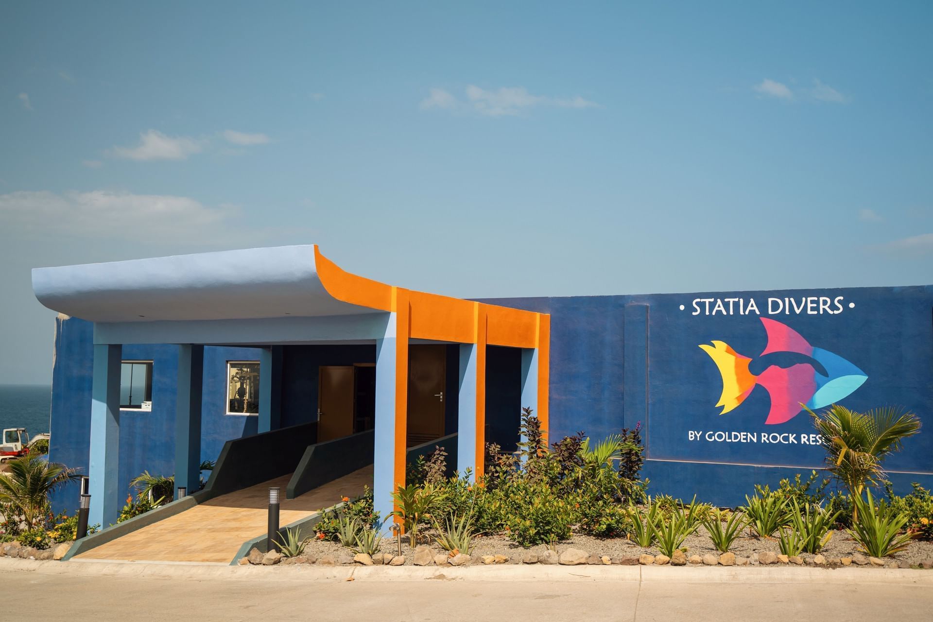 Buitenaanzicht van Statia Divers, met levendig blauwe muren en een kleurrijk vissenlogo bij Golden Rock Resort