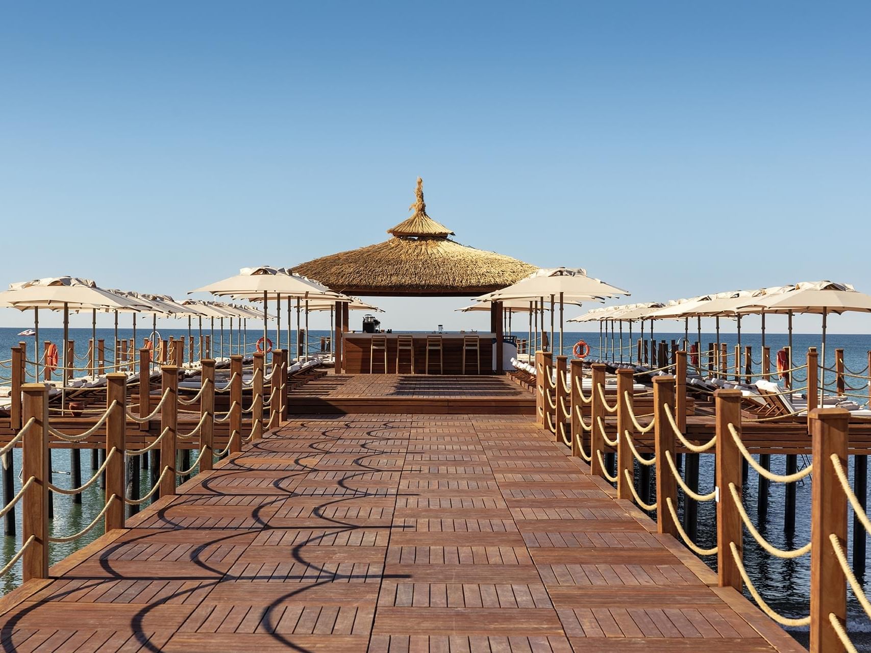 Seaside wooden deck with sun loungers, umbrellas and rope railings at Cullinan Belek's Pier