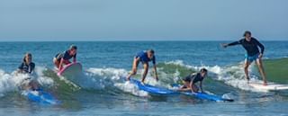 Surfers catching a wave during a surf lesson in Diamond Beach near our Wildwood Crest hotel
