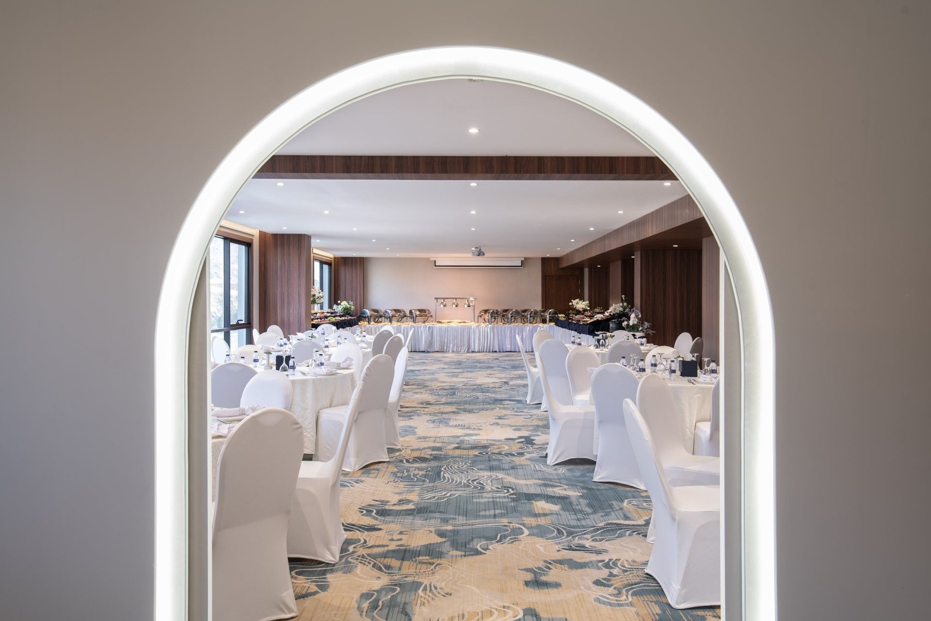 Dining tables with white chairs by an arched doorway under soft spotlights at Warwick Al Taif Hotel
