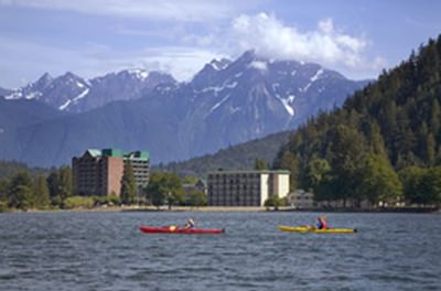 Two kayakers with view of hotel and mountains in the background.