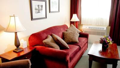 Elegant and bright living area of The Suite featuring a comfortable red couch and lamps in Pointe at Castle Hill